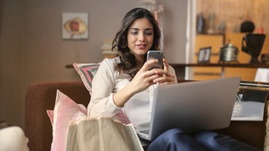 Woman uses her smartphone at home for FMCG e-commerce