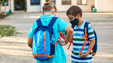 Deaf kid and kid wearing a mask and glasses talk