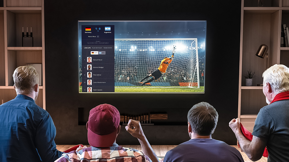 Gente emocionada viendo un partido de fútbol en la pantalla