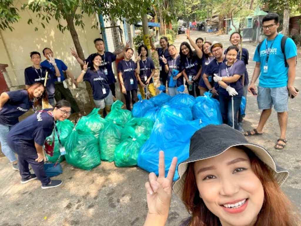 Group of volunteers pose by collected garbage