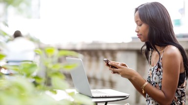 Mulher usando o telefone enquanto está sentada em um café na calçada
