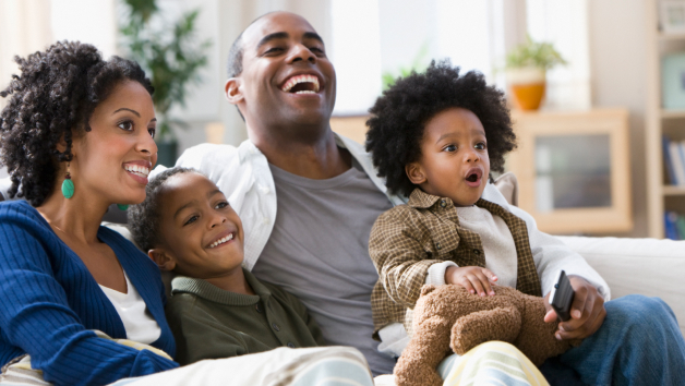 Sebuah keluarga berkulit hitam yang duduk bersama dan menikmati acara TV