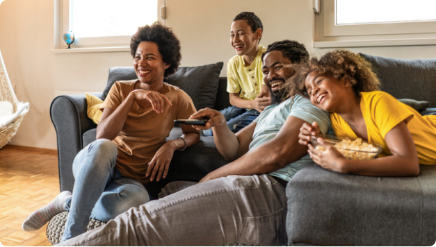 Una famiglia che si rilassa sul divano e si gode i programmi televisivi con gli snack