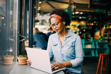 Giovane donna africana concentrata che lavora online in un caffè