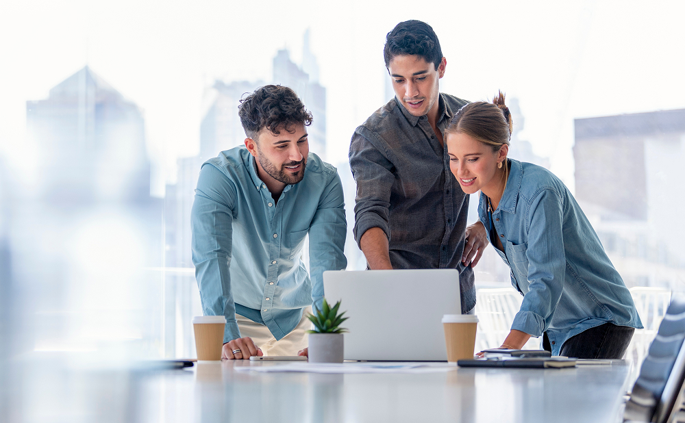 Three advertisers reviewing global insights on a laptop using Nelsen's cross media planning solution.