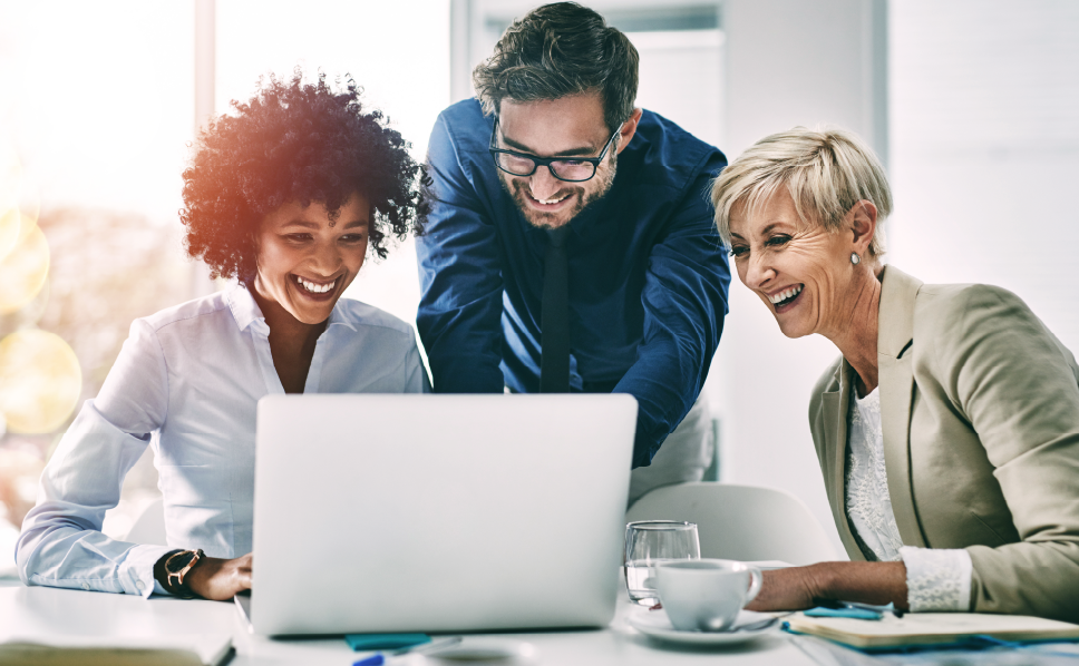 A group of marketers laughing and viewing untapped market opportunities on a laptop provided by Nielsen's streaming measurement solution.