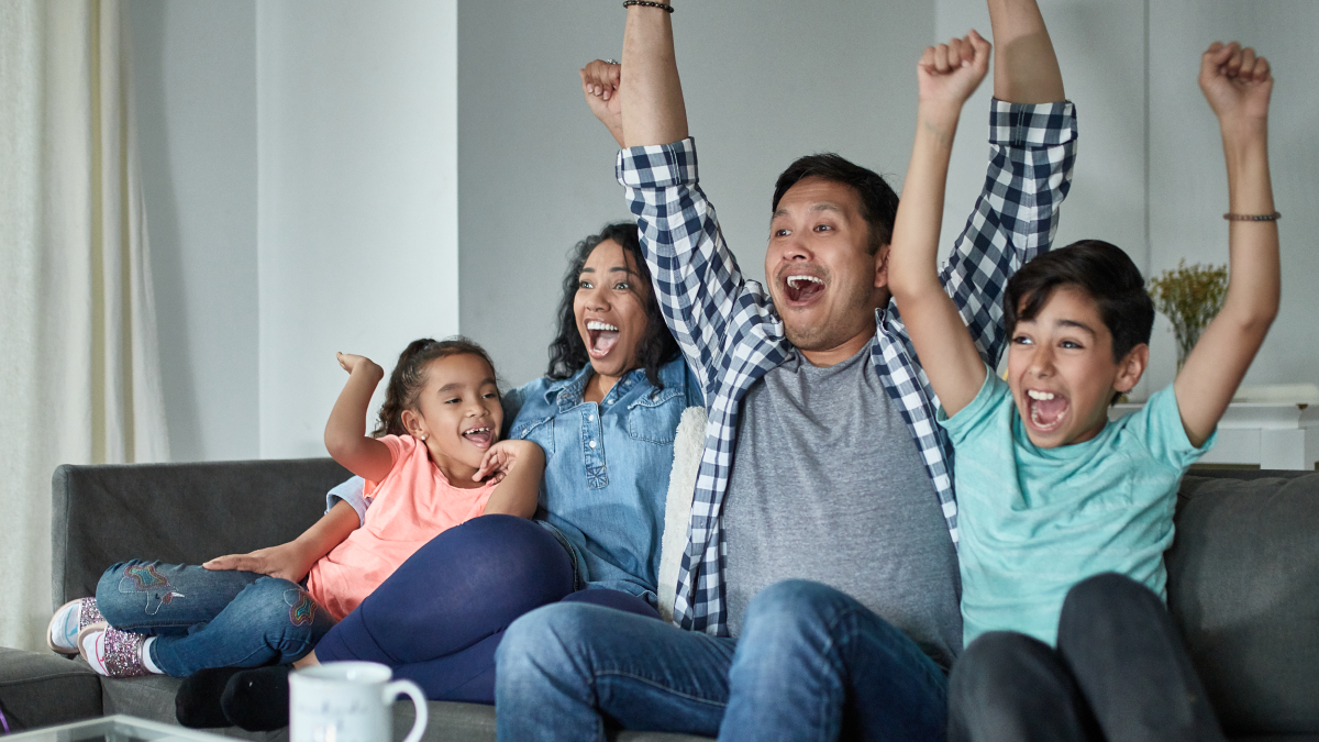 A family cheering and enjoying their TV show whose data will be collected via Nielsen's linear tv measurement.